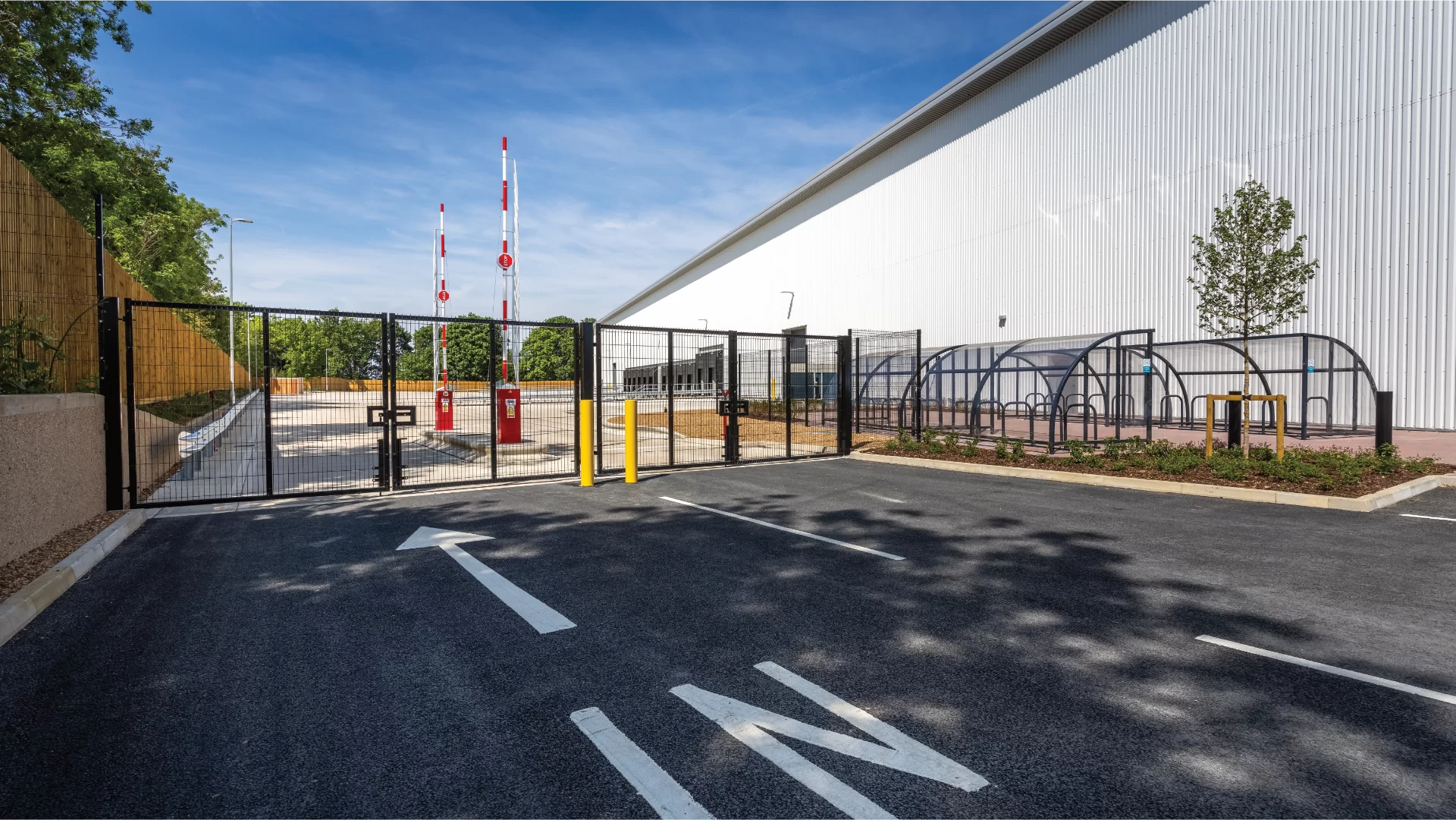 Gated industrial site entrance with parking bays.